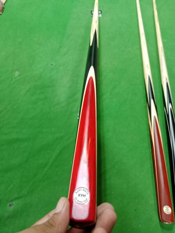 The XYH Handmade Snooker Cue, a premium professional cue stick crafted with precision, is designed for serious players who demand quality and performance. Featuring a 57 inch length, an 18oz balanced weight, and a 9.5mm tip size, this 3 piece snooker cue offers excellent control, spin, and accuracy. Made from high-quality ash wood, with a strong butt design, elegant red butt finish, and ebony splices, it combines both style and durability. The brass joint ensures long-lasting strength, while the smooth finishing provides a comfortable grip for consistent play. Whether you are looking for a professional snooker cue, handmade cue stick, billiard cue stick, or personal snooker cue, the XYH model is one of the best snooker cues in Pakistan, perfect for home, clubs, or tournaments.
